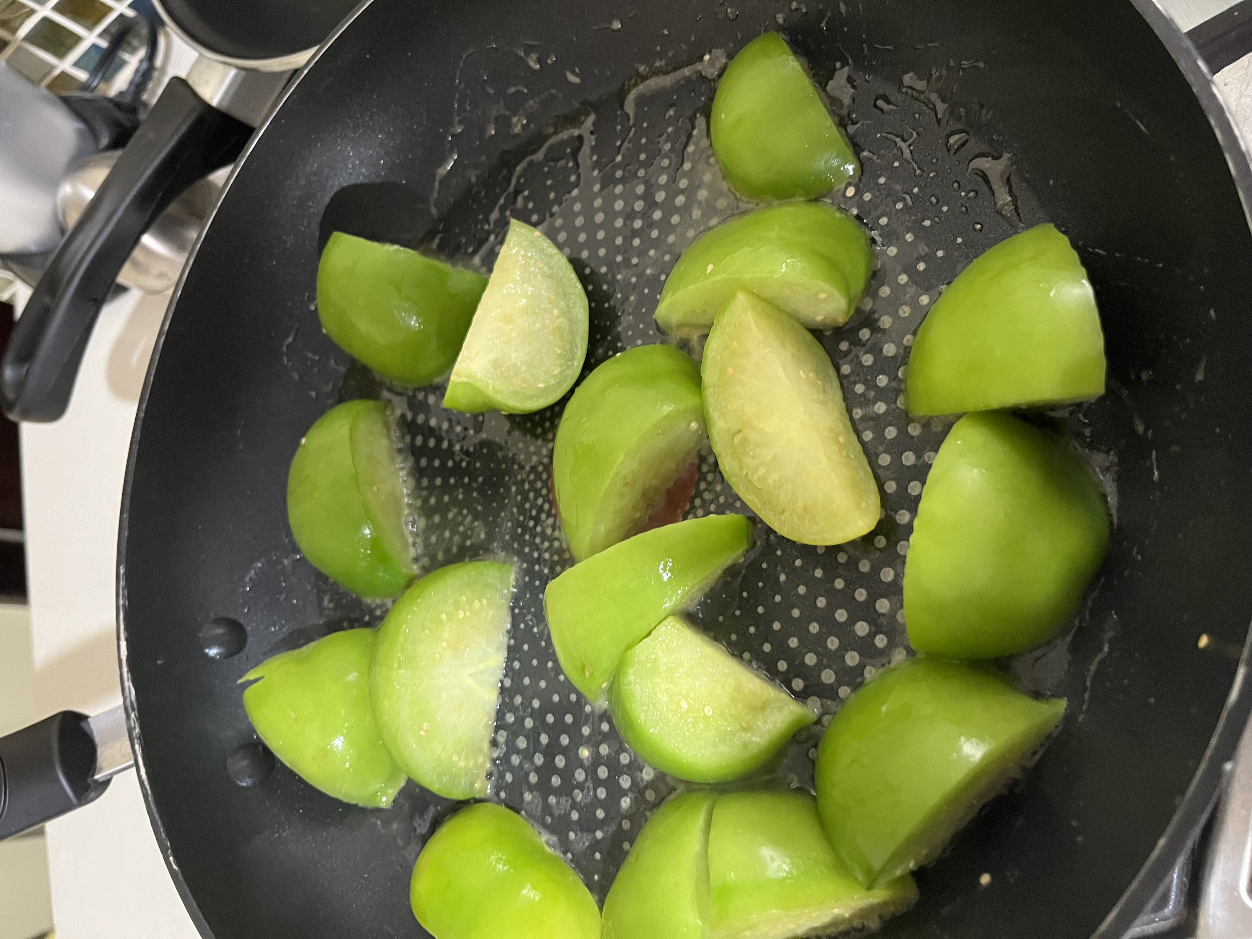 Fresh green tomatoes sizzling in a pan of butter. One of the first steps to making salsa verde.